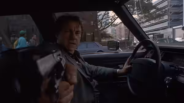 LT (Harvey Keitel) pointing a gun forward from the driver's seat