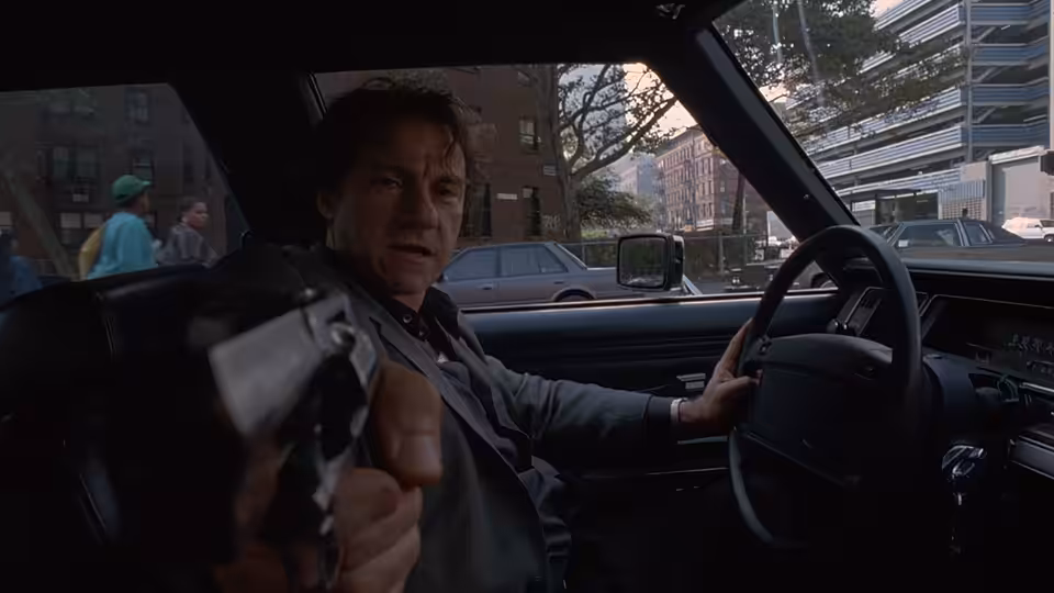 LT (Harvey Keitel) pointing a gun forward from the driver's seat