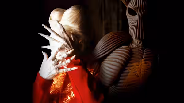 A pale figure in red covers their face with long clawed hands near a creature