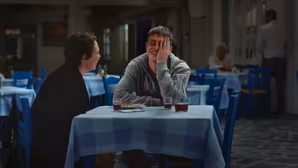 A woman and a young man sit across from each other at a restaurant table