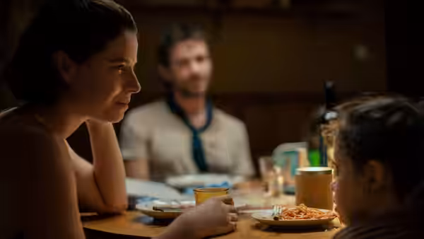 A woman and a man sit at a dinner table with a young girl