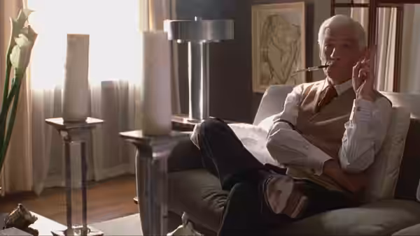 James Whale (Ian McKellen) reclining on a couch while smoking a pipe