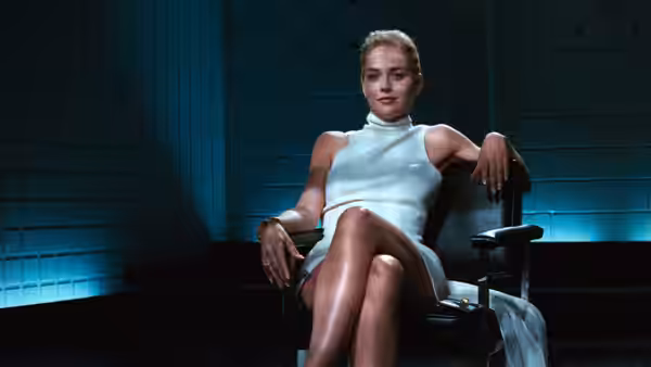 Catherine Tramell (Sharon Stone) seated in a blue interrogation room chair