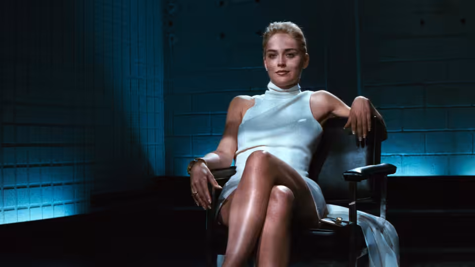 Catherine Tramell (Sharon Stone) seated in a blue interrogation room chair