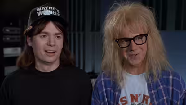 Wayne Campbell (Mike Myers) and Garth Algar (Dana Carvey) seated together indoors