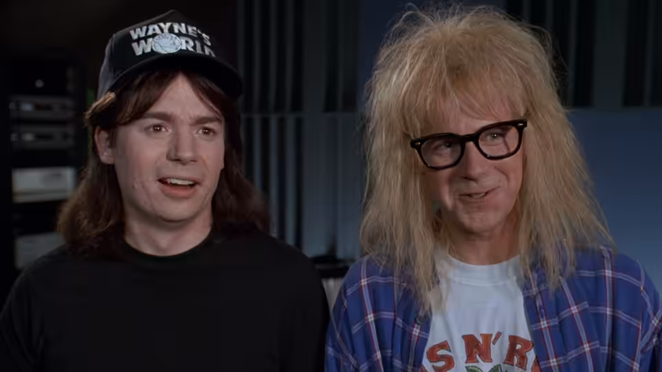 Wayne Campbell (Mike Myers) and Garth Algar (Dana Carvey) seated together indoors