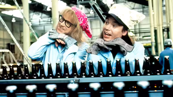 Wayne Campbell (Mike Myers) and Garth Algar (Dana Carvey) standing at a factory bottling line