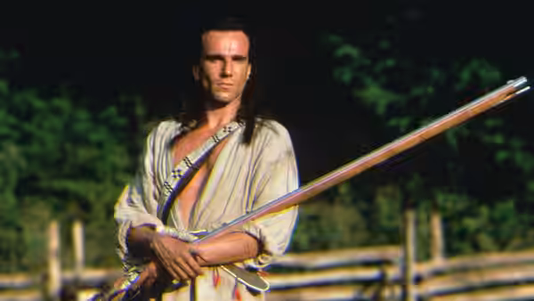 Hawkeye (Daniel Day-Lewis) standing outdoors holding a long rifle across his body