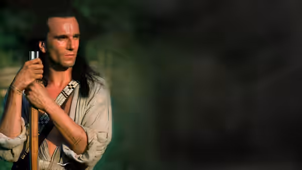 Hawkeye (Daniel Day-Lewis) carrying a rifle over his shoulder in the woods