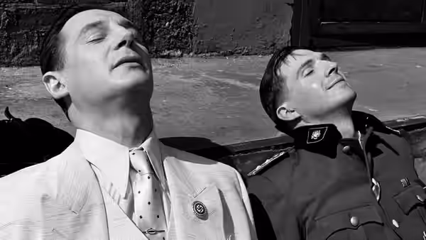 Two men leaning back against a wall with eyes closed in sunlight