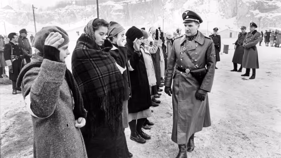 German officer facing a line of civilians with hands on their faces in snow