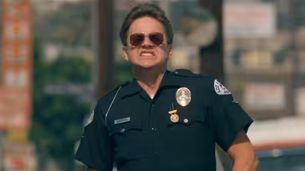 Police officer in sunglasses standing on a street with a stern expression