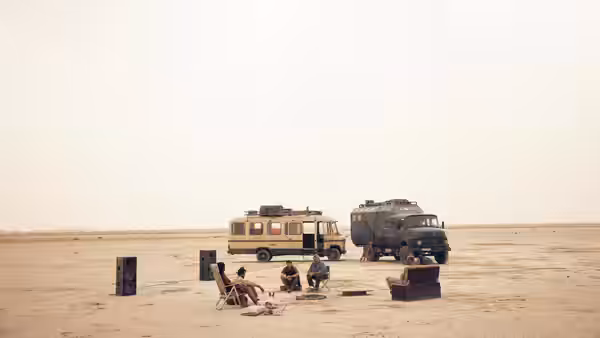 people sitting in chairs beside two vehicles in a desert