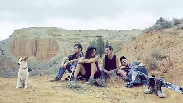 young people and a dog resting on a rocky hillside