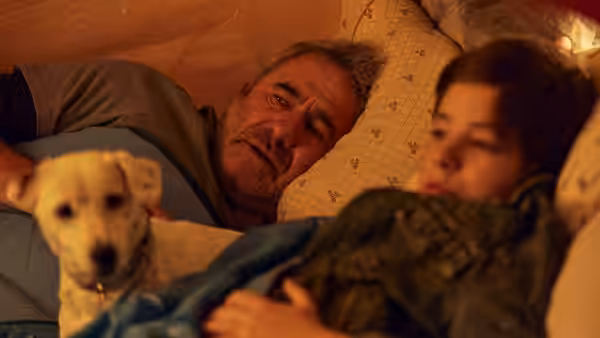 Luis (Sergi López) and Esteban (Bruno Núñez) lying in bed with a dog