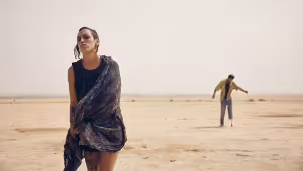 woman standing in the desert with a man in the distance