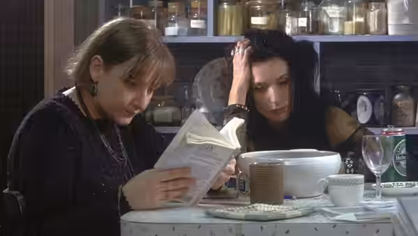 Louise (Lesley Sharp) reading book beside Sophie (Katrin Cartlidge) at table