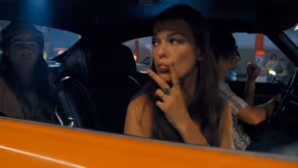Young woman in the front seat of a car at night with her finger near her mouth