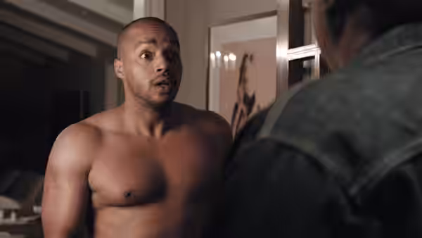 Ward (Donald Faison), shirtless, speaks to another man inside a home