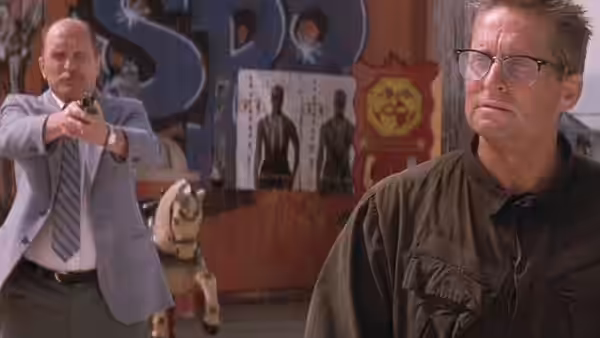 Prendergast (Robert Duvall) aiming handgun past D-Fens (Michael Douglas) in arcade