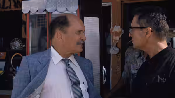 Prendergast (Robert Duvall) facing man in black shirt outside shop entrance