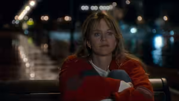 Annie Reed (Meg Ryan) sits on a bench with arms crossed at night