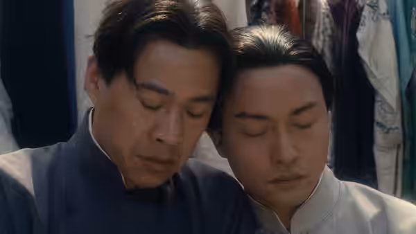 Two men in traditional attire resting heads together eyes closed