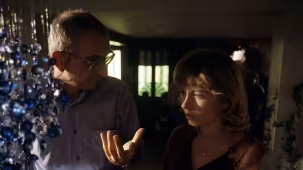 A man gesturing to a woman while examining strands of blue crystals