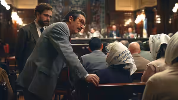 Julio Strassera (Ricardo Darín) addresses witnesses wearing head coverings in a crowded courtroom