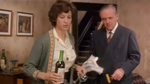 a woman holding a wine bottle beside a man with broken glass