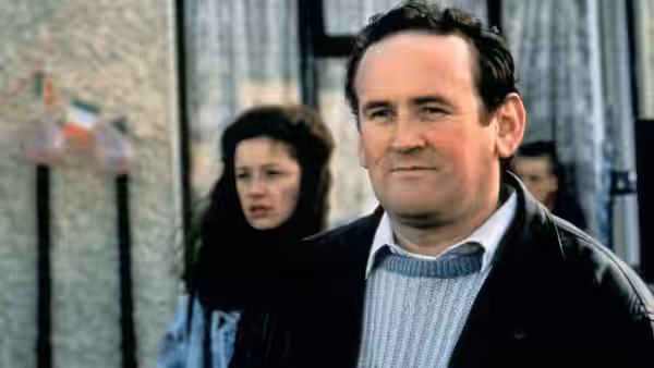 Dessie Curley (Colm Meaney) standing outside with a woman behind him