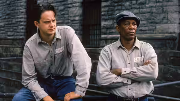 Andy Dufresne and Red seated side by side against stone wall
