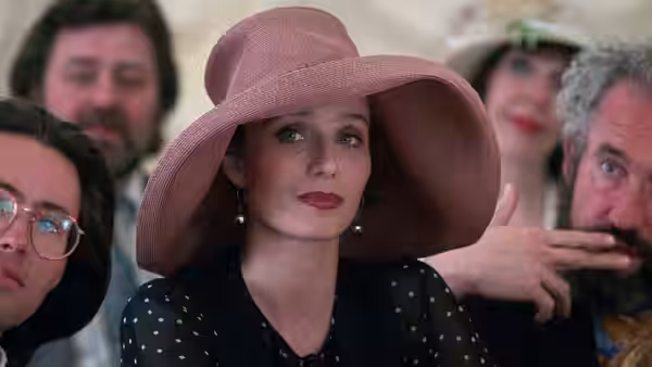 Fiona (Kristin Scott Thomas) in a wide pink hat looks upward at an event