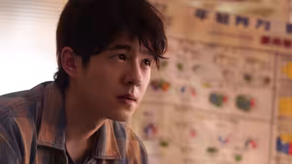 Wu Youwei (Liu Haoran) looks intently toward someone beside a newspaper-covered wall