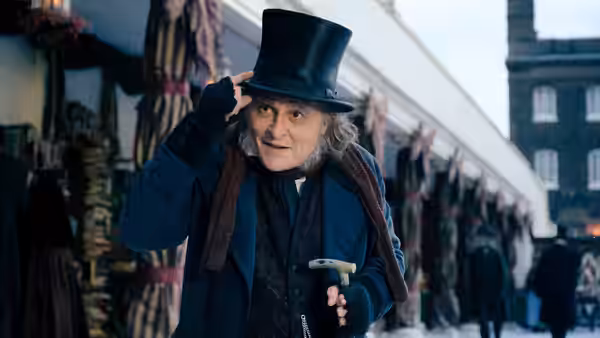 Ebenezer Scrooge (Johnny Depp) tips his top hat on a crowded Victorian street