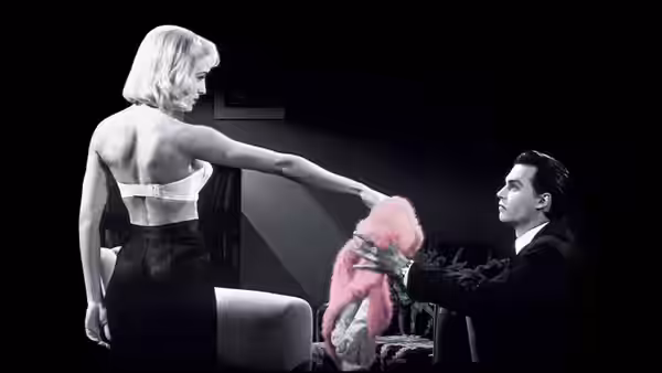 A woman in a backless dress handing a pink boa to Ed Wood