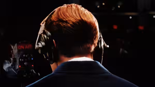 Charles Van Doren (Ralph Fiennes) seen from behind wearing headphones in a studio