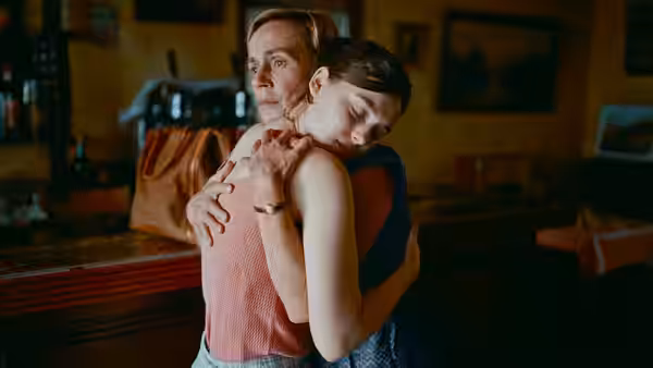 A woman leans back against a man holding her in a warmly lit room