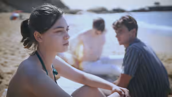 Anne Duchesne (Anamaria Vartolomei) sits on a beach as two young men linger behind her