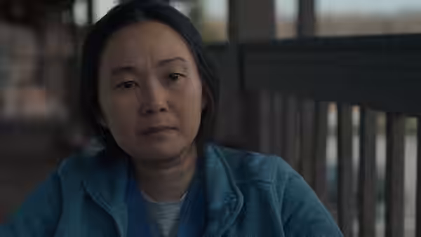 Liz (Hong Chau) sits near a railing in a blue fleece jacket