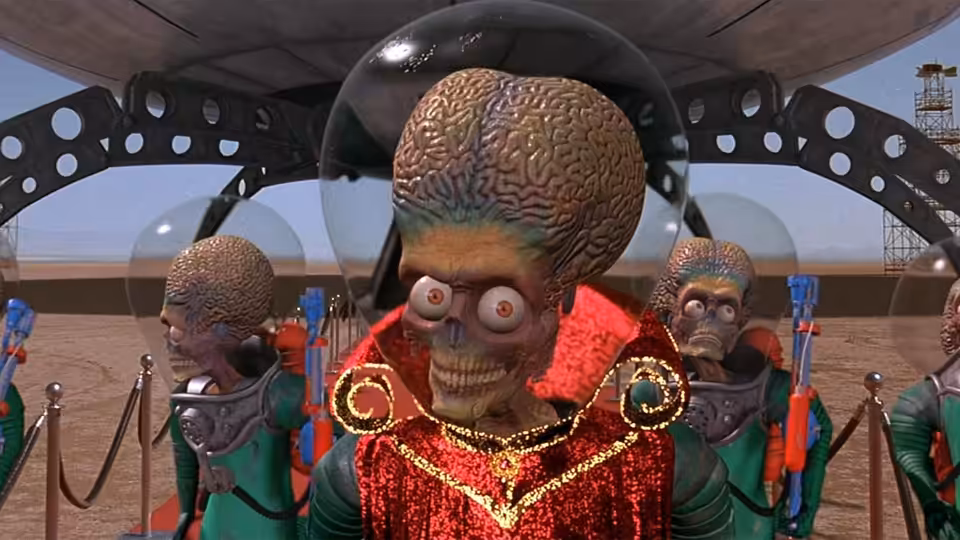 A giant-brained Martian in a red uniform stands with his crew