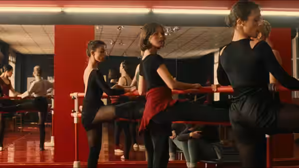 Valentine (Irène Jacob) stretching at the barre in a dance studio with other dancers