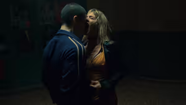 A man and woman stand face to face in a dark room