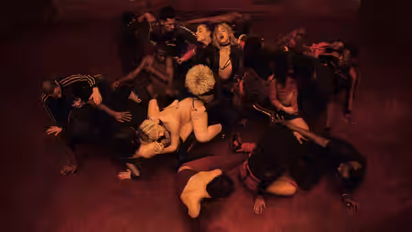 A crowd of people lies entangled on a red-lit floor