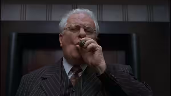 Elderly man in pinstripe suit smoking a cigar in a formal office