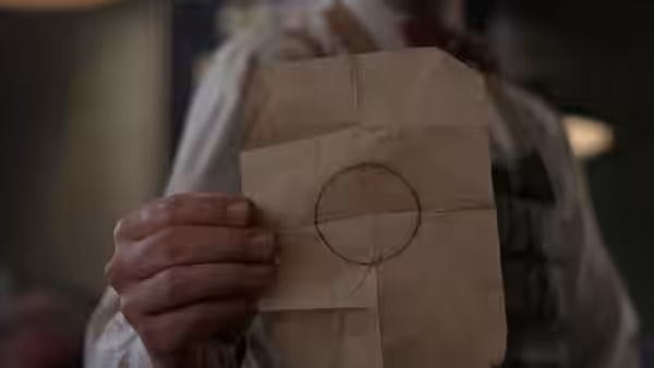Hands holding a crumpled paper bag marked with a large circle