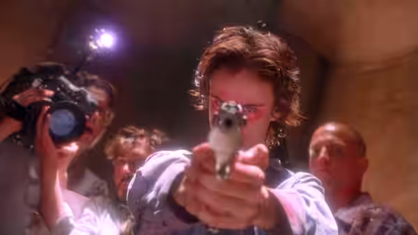 Wayne Gale (Robert Downey Jr.) pointing pistol at camera with film crew behind