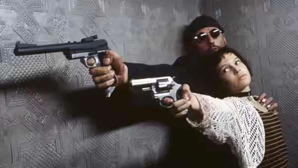 Léon (Jean Reno) and Mathilda (Natalie Portman) aiming handguns against a wall