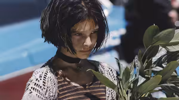Mathilda (Natalie Portman) with wet hair standing near green leaves