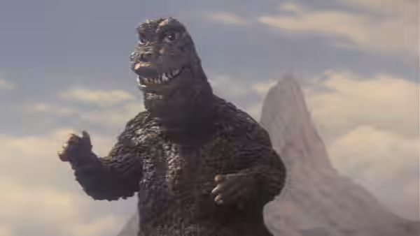 Godzilla raises his hands before a volcanic peak